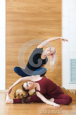 Two smiling women do stretching exercise in sports club. Fitness gym. Stock Photo