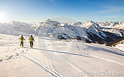 Two snowshoe hikers at sunset in alpine winter mountains. Bavaria, Germany. Stock Photo