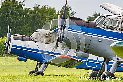 Two soviet aircrafts biplane Antonov AN-2 parked on a green grass of airfield closeup Stock Photo