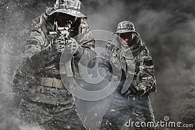 Two Special forces soldiers men holding a machine gun on dark background Stock Photo