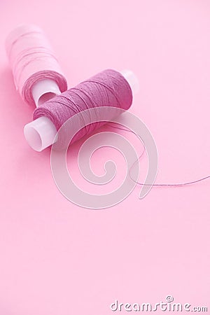 Two spools of sewing thread lilac pink, violet, crimson on a pink backgroun. Stock Photo