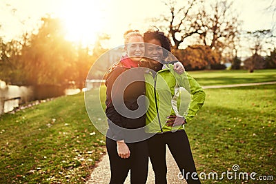 Two sportswomen in park hugging and looking at camera Stock Photo