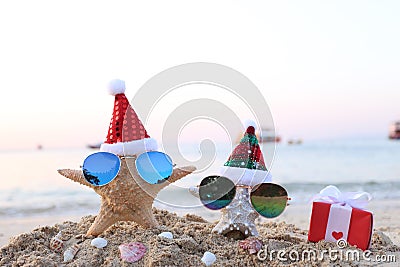 Two starfish on sea beach with sunglasses and santa hat for Merry Christmas and New Years Stock Photo