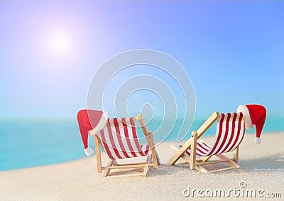 Two striped sunloungers with Christmas Santa hats at ocean sunset beach Stock Photo