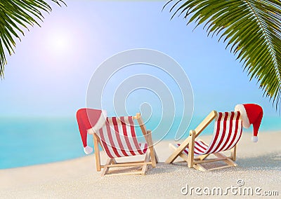 Two striped sunloungers with Christmas Santa hats at ocean sunset palm beach Stock Photo