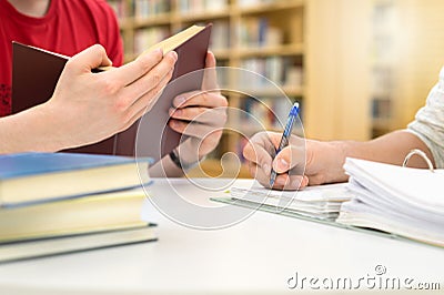 Two students studying, reading and writing in library. Stock Photo