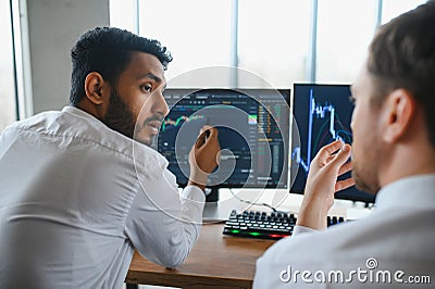 Two successful trader in formalwear pointing at display, analyzing stat and dynamic on forex charts, working in office Stock Photo
