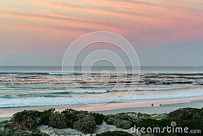 Two surfers sitting on Betty`s Bay beach at sunset in the Western Cape, South Africa Stock Photo
