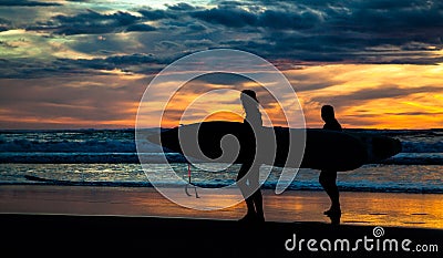 Two surfers on Piha Beach in sunset Stock Photo
