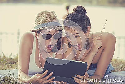 Two surprised girls looking at pad discussing latest gossip news Stock Photo