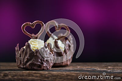 Two sweet chocolate desserts filled with white cream and with hearts on purple background, valentines or wedding cake Stock Photo