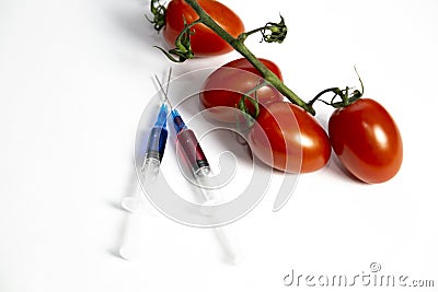 Two syringes with chemicals near a branch of tomatoes Stock Photo