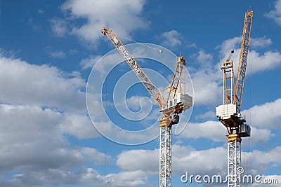 Two tall cranes with cabin in which the operator controls the crane on a construction site Editorial Stock Photo