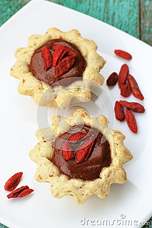 Two tasty homemade fancy cakes with chocolate cream and dry goji Stock Photo