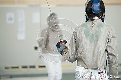 Two teenager fencers in white protective clothes fighting on the fencing tournament Stock Photo