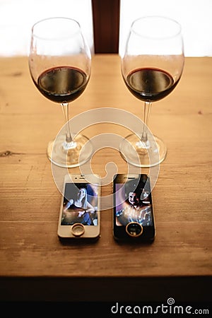 Two telephones, rings and two glasses of wine on a table Stock Photo
