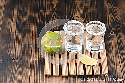 Two Tequila shots with lime slices and salt on wooden table/Tequila shots and lime slice on wooden table with Copy cpace. Top view Stock Photo