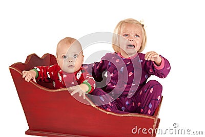 Two toddlers in sleigh one is sad and crying Stock Photo