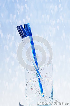 Toothbrushes kiss in a glass on the background of hearts Stock Photo