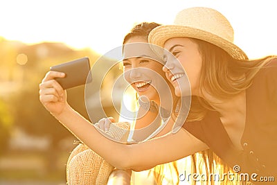 Two tourist friends taking selfies in hotel balcony Stock Photo