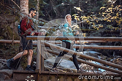 Two travel hikers with backpack walking on the wood bridge while looking the landscape in the forest Stock Photo