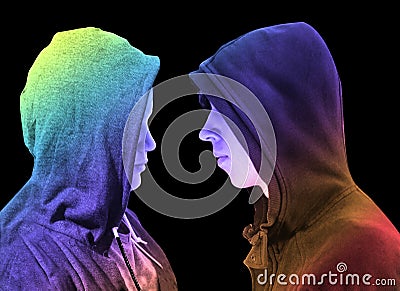 Two troubled teenage boys with black hoodie standing in front of each other in profile isolated on black background. Creative colo Stock Photo