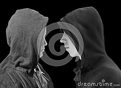 Two troubled teenage boys with black hoodie standing in front of each other in profile isolated on black background. Black and whi Stock Photo