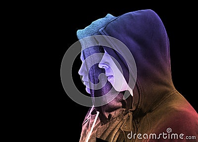 Two troubled teenage boys with black hoodie standing next to each other in profile isolated on black background. creative colorful Stock Photo