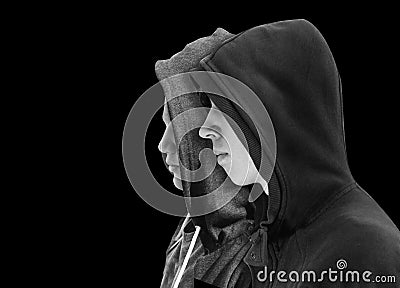 Two troubled teenage boys with black hoodie standing next to each other in profile isolated on black background. Black and white i Stock Photo