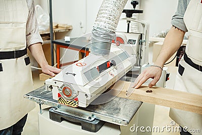 Two turners holding wooden bar on drum-grinding machine with oscillation Stock Photo