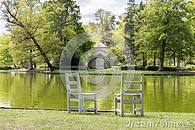 Two unoccupied wooden chairs overlooking a peaceful lake Stock Photo