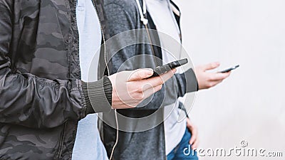 Two unrecogniazble mobile phone addicted male teenagers using smartphone Stock Photo