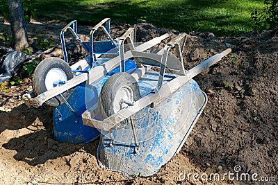 Two used, blue, dirty wheelbarrows turned upside down in the dirt Stock Photo