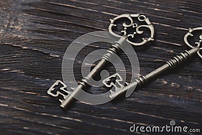 Two vintage bronze keys on a wooden table Stock Photo