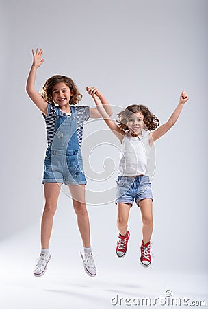 Two vivacious lively little girls jumping together Stock Photo