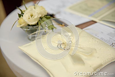 Two wedding platinum rings lying on silk lace cushion for rings Stock Photo