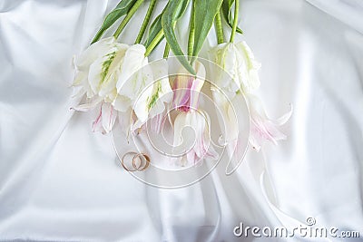 Two wedding rings and bouquet of white tulips Stock Photo