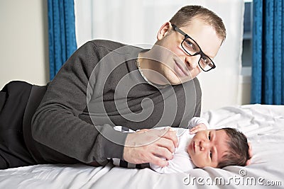 Two week newborn baby with father in bed Stock Photo