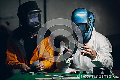 Two welders in welding masks play poker. Editorial Stock Photo