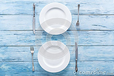 Two white empty plates and cutlery on blue table. Stock Photo