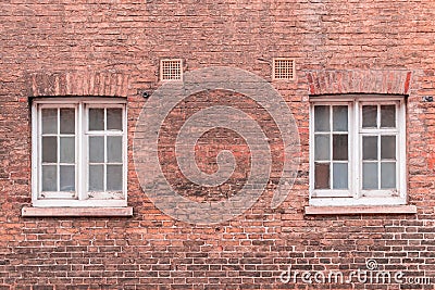 Two white wooden sash windows on a restored red brick wall of a Stock Photo