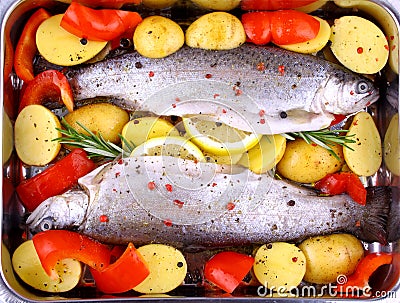 Two whole rainbow trout with red pepper, potato and lemon Stock Photo