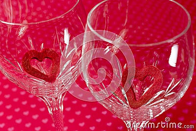 Two wine glasses with red felt cutout hearts inside, soft floral Stock Photo