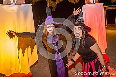 Two witches with scary face paint make up during Halloween party at the artificial cemetery on the beach Editorial Stock Photo