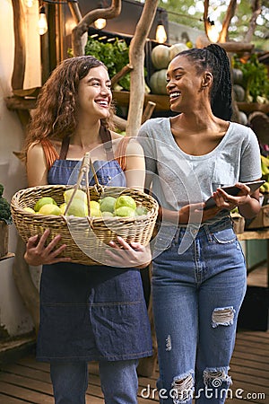 Two Women With Basket Of Lemons And Digital Tablet Working At Fruit And Vegetable Stall In Market Stock Photo