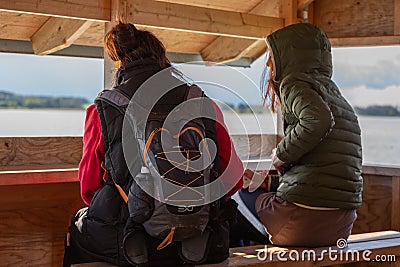 Two women communicate with each other and look at the water. Sitting on the observation tower. Back view Editorial Stock Photo