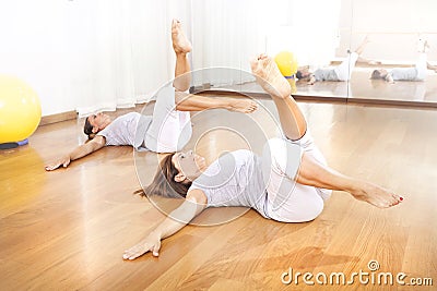 Two women crossing legs in synchrony for fitness Stock Photo