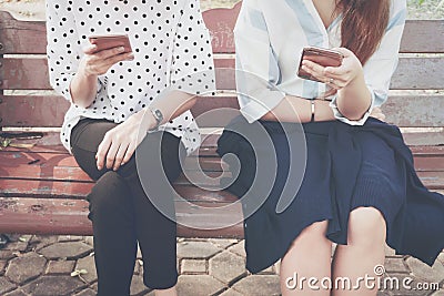 Two women in disinterest moment with smart phones in the outdoor, concept of relationship apathy and using new technology. Stock Photo