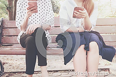 Two women in disinterest moment with smart phones in the outdoor, concept of relationship apathy and using new technology and smar Stock Photo