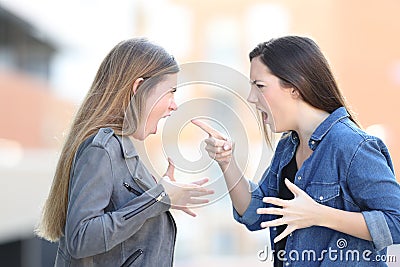 Two women fighting shouting each other in the street Stock Photo